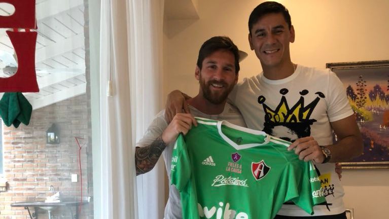 Messi poses with Atlas jersey.